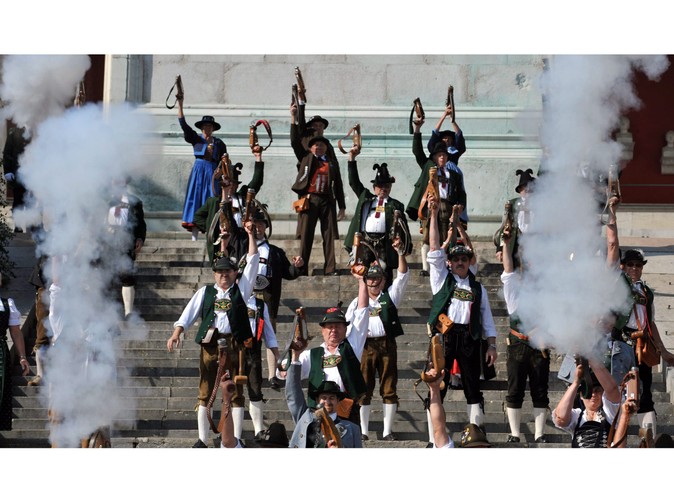 Mężczyźni ubrani w tradycyjne stroje oddają salwę oznajmiającą koniec Oktoberfest