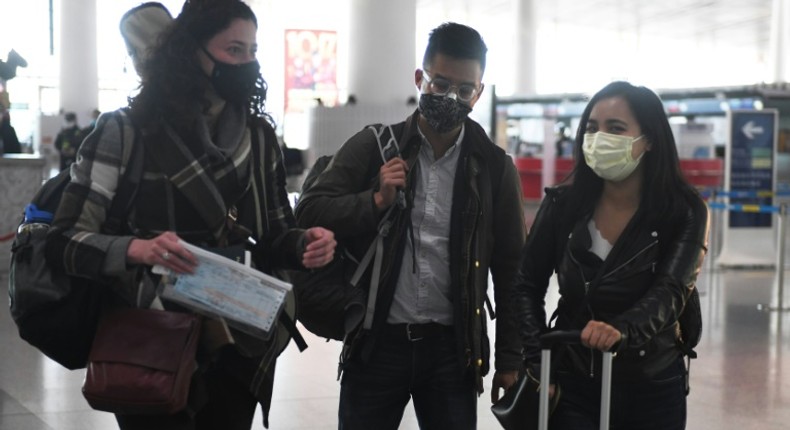 Wall Street Journal reporters Julie Wernau (L), Stu Woo (C) and Stephanie Yang walk through Beijing Capital Airport before departing