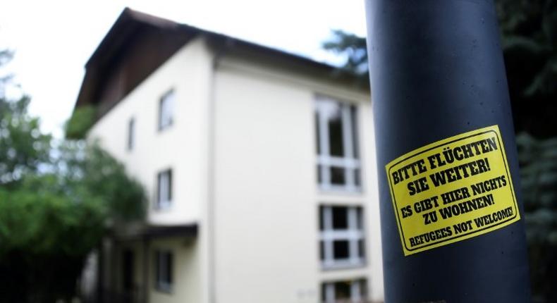 A sticker reading 'Please keep on fleeing - here is no place for you - refugees not welcome' is pinned at a lantern next to a refugee centre in Freital, eastern Germany