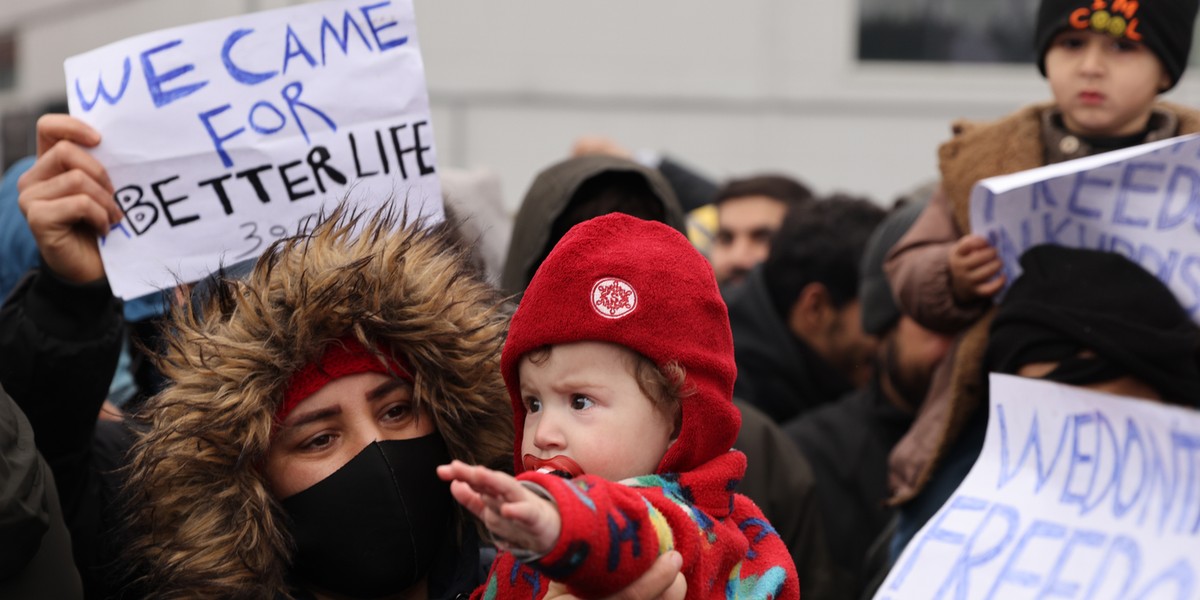 Migranci zgrupowani w centrum logistycznym w Bruzgi pod Grodnem trzymają plakaty, na których można m.in. przeczytać: "Przyszliśmy po lepsze życie".