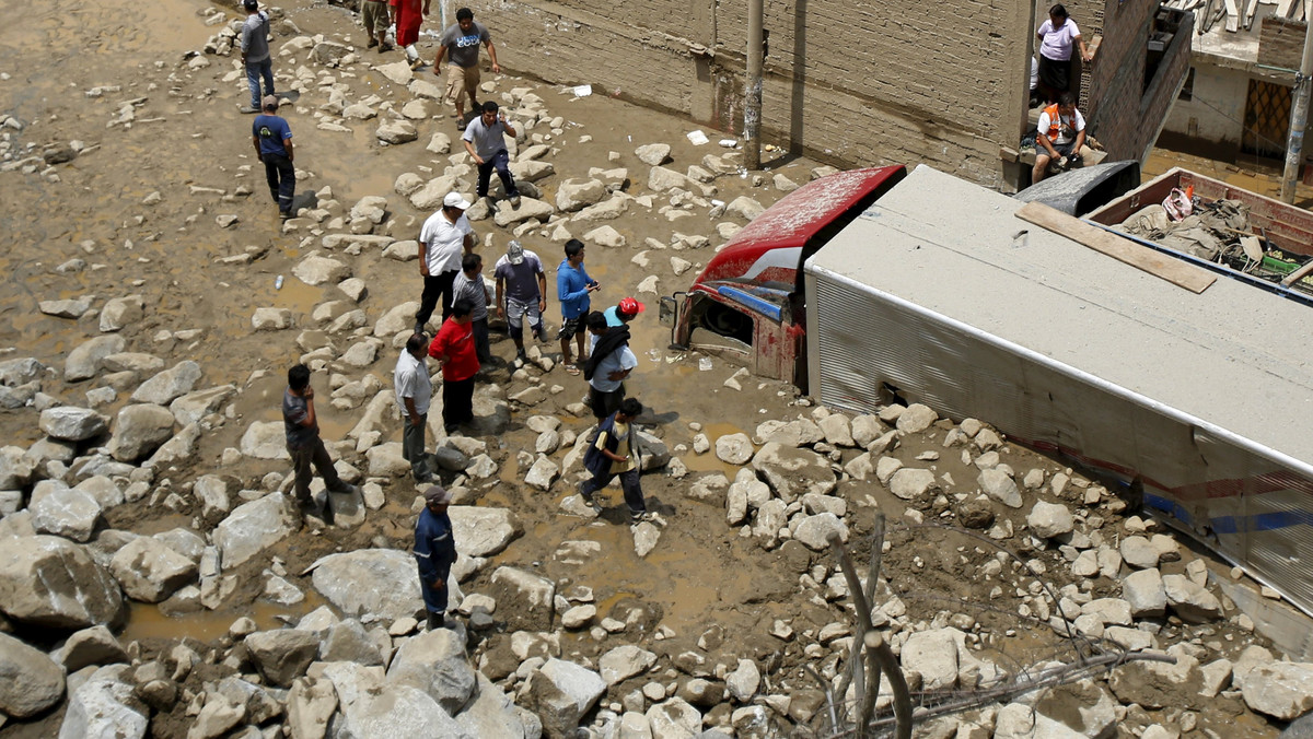 People look at a truck stuck in the mud and stones after a landslide at the Carretera Central highway in Chosica