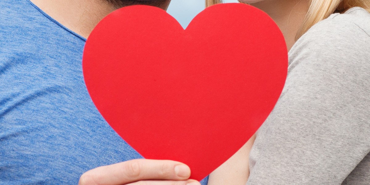 happy couple with red heart shape hugging outdoors