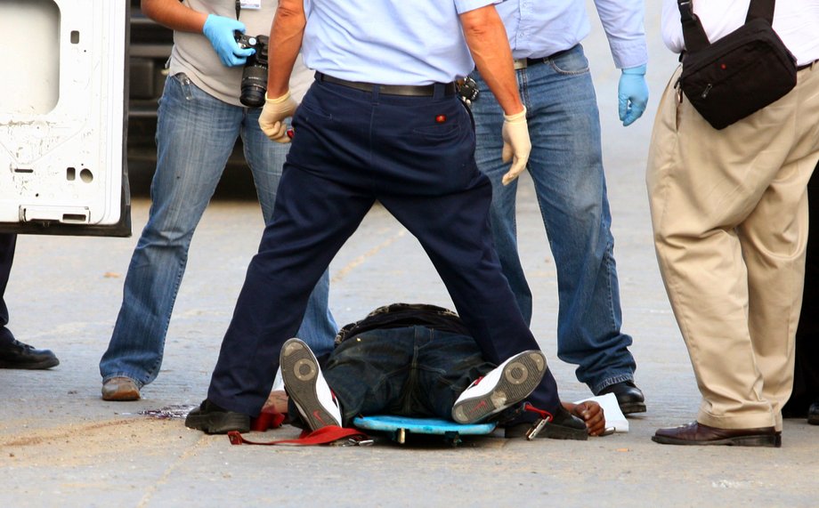 Forensic workers stand over the headless body of a man in Tijuana, October 12, 2010.