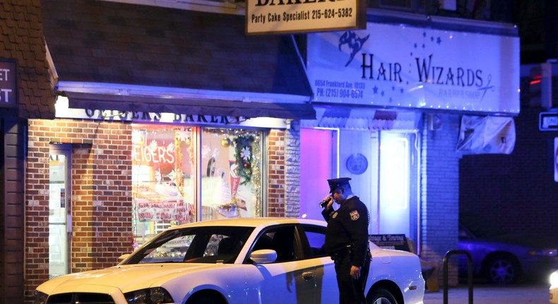 A police officer looks over a car in Philadelphia, Monday, Dec. 15, 2014, that was being driven by a man who police shot and killed during an early morning traffic stop.
