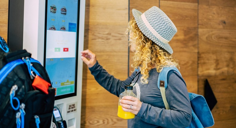 Woman ordering from fast-food restaurant on a digital screensimonapilolla/Getty