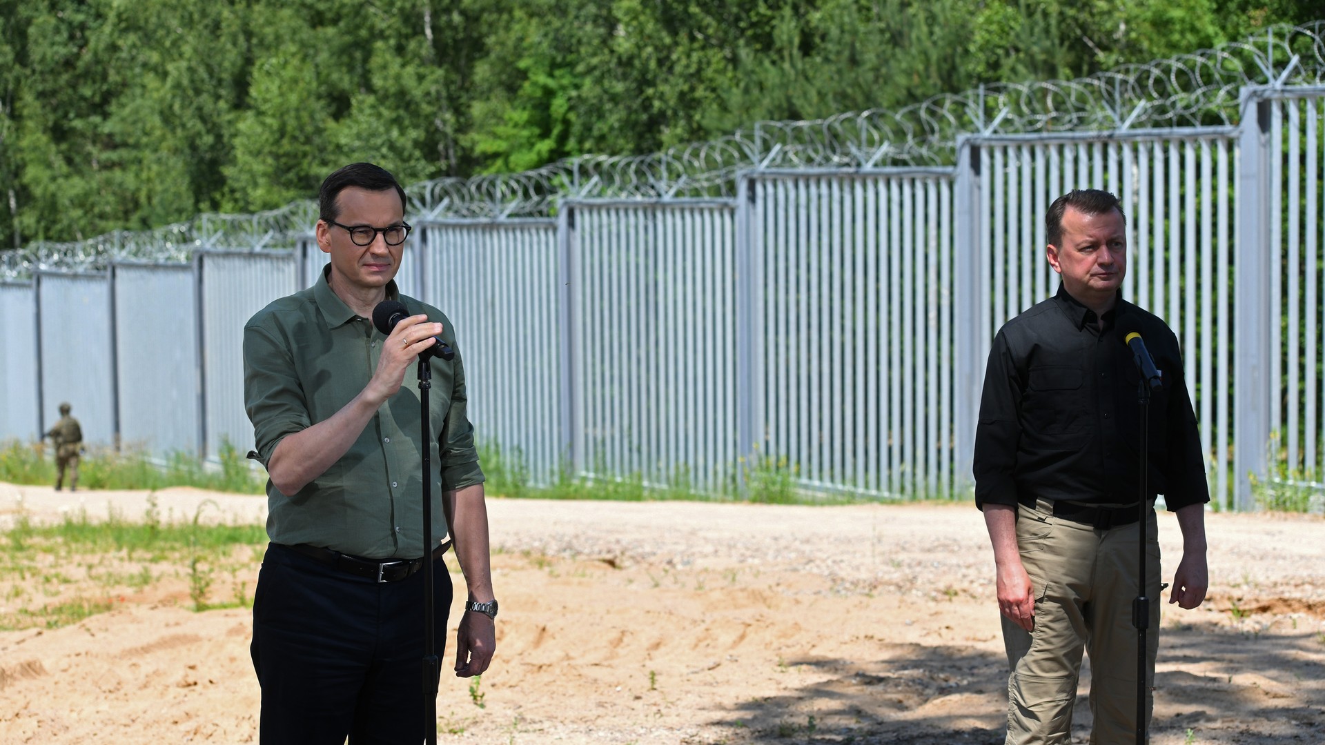 Mateusz Morawiecki i Mariusz Błaszczak w czasie konferencji prasowej przy płocie na granicy z Białorusią