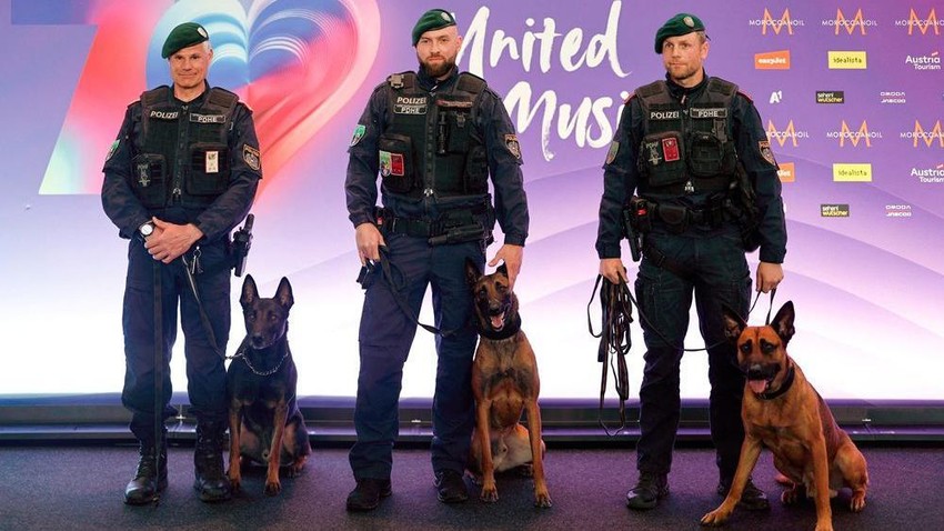 Austrijski policajci poziraju sa dresiranim psima ispred evrovizijskog panoa | Foto: REUTERS/Lisa Leutner