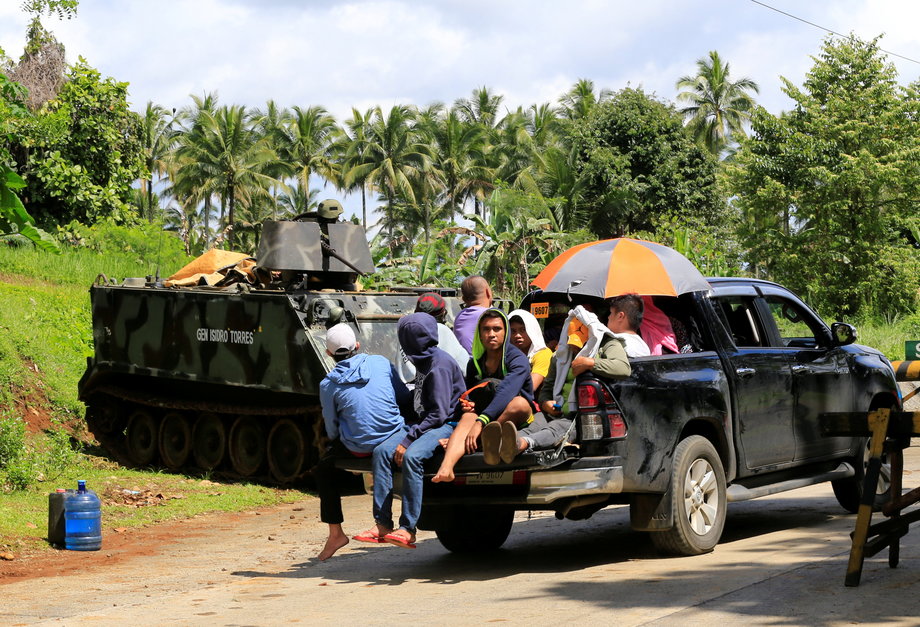 Evacuees drive past government troops on an armored personnel carrier along a main highway of Pantar town, Lanao Del Norte, after residents started to evacuate their hometown of Marawi city, southern Philippines, May 24, 2017.