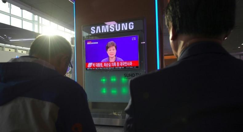 People watch a television news report showing South Korean President Park Geun-Hye making a public apology, at a railway station in Seoul.