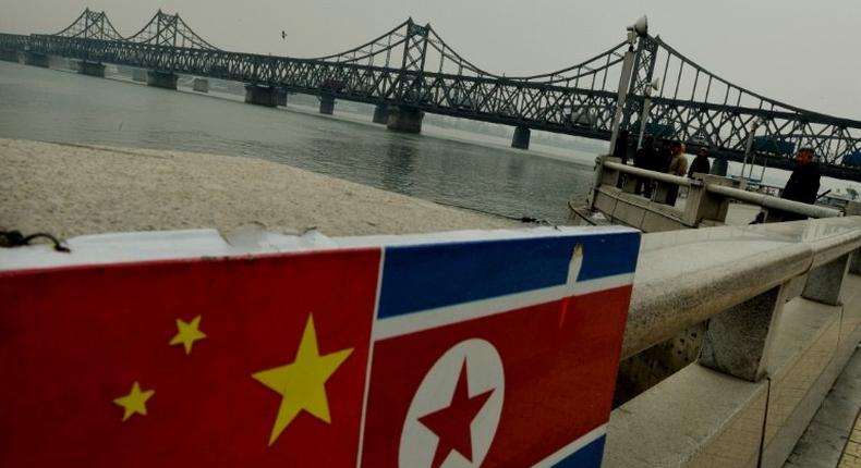 The Chinese and North Korean flags attached to a railing as trucks carrying Chinese-made goods cross into North Korea on the Sino-Korean Friendship Bridge at the Chinese border town of Dandong on December 18, 2013