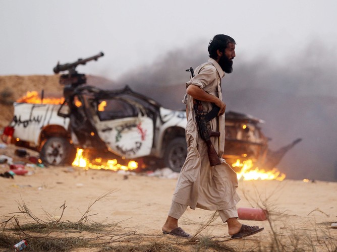 Libijski rebeliant obok samochodu zniszczonego przez zwolenników reżimu Kadafiego. Sirte, Libia, 8 października 2011