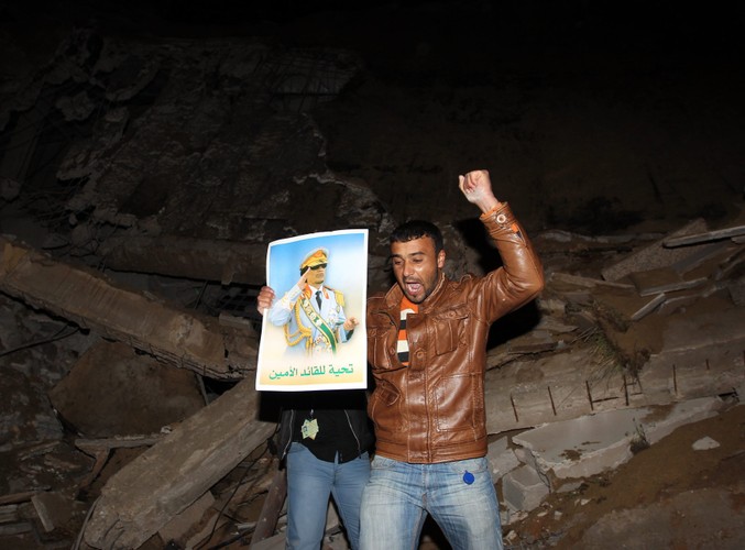 Libijczycy na gruzach budynku w Trypolisie, należącego do administracji Muammara Kadafiego, położonego zaledwie 50 metrów od namiotu, w którym Kadafi przyjmuje gości