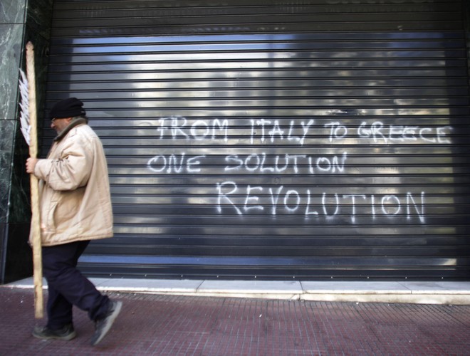Grecki dług jest rozporoszony po wielu bankach, toteż w przypadku jej bankructwa żadnemu nie grożą poważne problemy. Grecja jest obecnie zadłużona w zagranicznych instytucjach finansowych na „jedynie” na 46 mld dol., podczas gdy w 2010 roku kwota ta wynosiła 300 mld dol. Na fot. protestujący przechodzi obok graffiti w języku angielskim 'Od Włoch do Grecji, jedno rozwiązanie - rewolucja' na ulicach Aten, stolicy Hellady