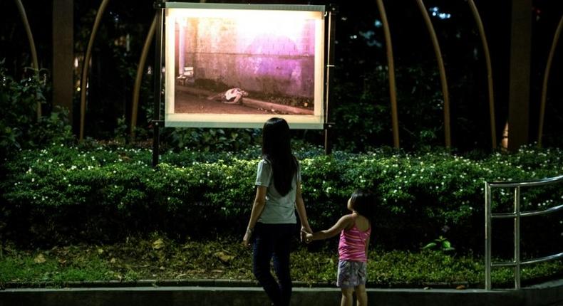 Churchgoers look at an exhibit of pictures showing the deaths of alleged drug dealers and users outside Baclaran Church in Manila