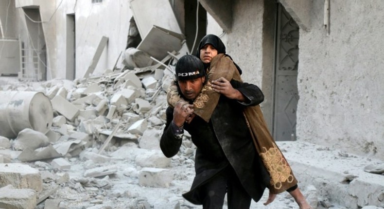 A Syrian rescuer carries a woman from the rubble of a building in Aleppo on November 20, 2016