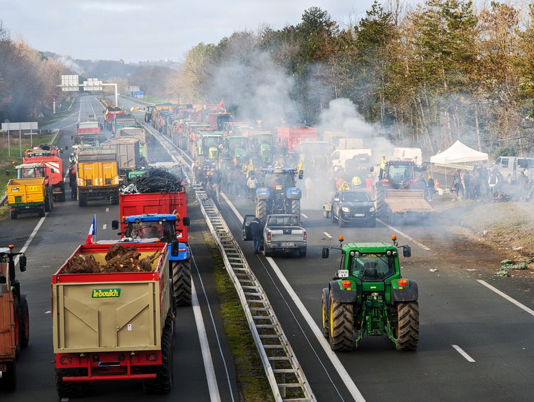 Francuscy rolnicy palą słomę i blokują jezdnię w okolicach miasta Agen, protestując przeciwko polityce podatkowej i spadkowi dochodów, styczeń 2024 r.