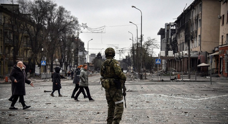 People pass by a Russian soldier in central Mariupol on April 12, 2022.