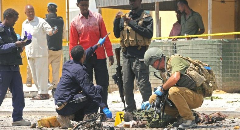 A foreign security officer checks a body at the scene of a suicide attack in Mogadishu, on July 31, 2016 