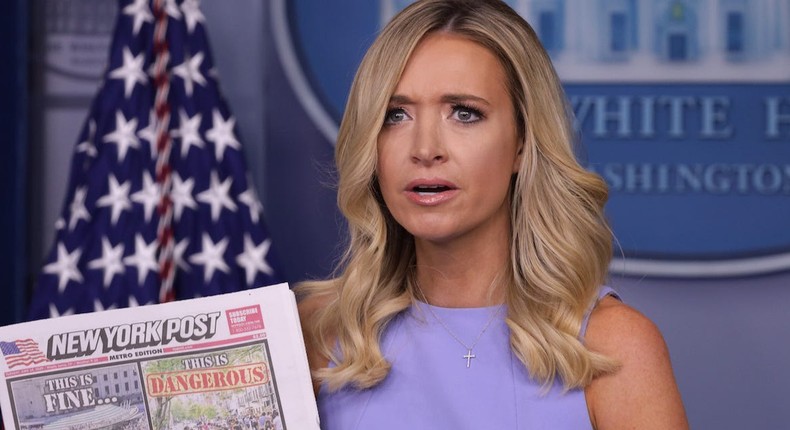 Former White House press secretary Kayleigh McEnany holds up a copy of the New York Post in the briefing room.