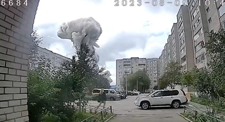 A screen grab from a CCTV footage shows broken windows and a person walking in a residential area, with smoke billowing in the background, following a blast at a factory in Sergiev Posad, Russia, August 9, 2023.Reuters