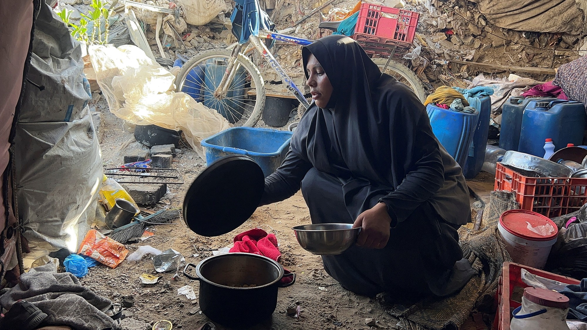 Palestínčanka Amani Maaroufová sedí s kovovou miskou s cestovinami pred svojím stanom, v ktorom sa ukryla po vysídlení, v meste Gaza.