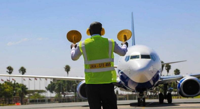 An aircraft marshal guides a plane at JKIA