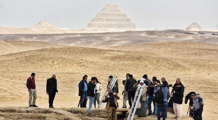 Fotóriporterek egy nemrégiben felfedezett sír bejáratánál az egyiptomi Gíza közelében 2022. március 19-én. 