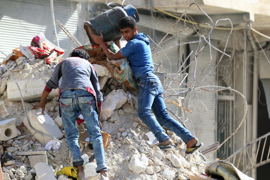 People remove belongings from a damaged site after an air strike in the rebel-held besieged al-Qaterji neighborhood of Aleppo, Syria.
