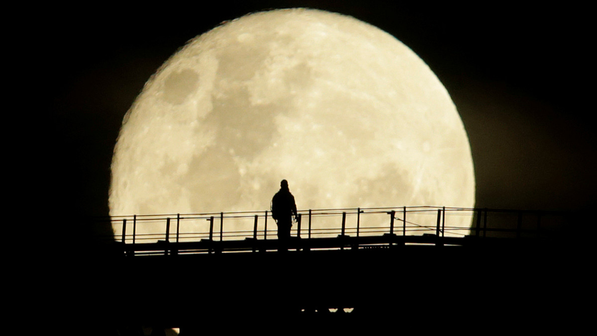 A man walks on the top span of the Sydney Harbour Bridge as the supermoon enters its final phase in Sydney