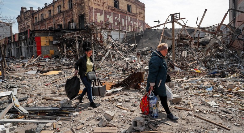 Residents carry their belongings near buildings destroyed in the course of Ukraine-Russia conflict, in the southern port city of Mariupol, Ukraine April 10, 2022.