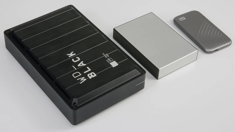Zewnętrzny dysk twardy jest znacznie większy niż zewnętrzny dysk SSD (po prawej): Dotyczy to modeli 2,5-calowych, takich jak Seagate Backup Plus Portable (w środku). Szczególnie duże i ciężkie są 3,5-calowe dyski twarde, takie jak WD Black D10 (po lewej)