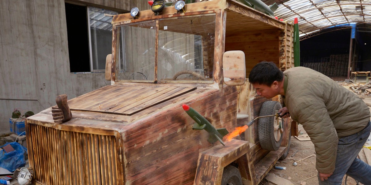 A carpenter torches his homemade wooden electric car for a vintage look.