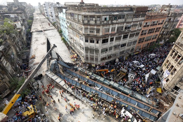 Firefighters and rescue workers search for victims at the site of an under-construction flyover afte