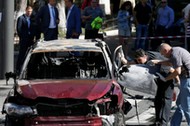 Investigators inspect a damaged car at site where journalist Pavel Sheremet was killed by a car bomb