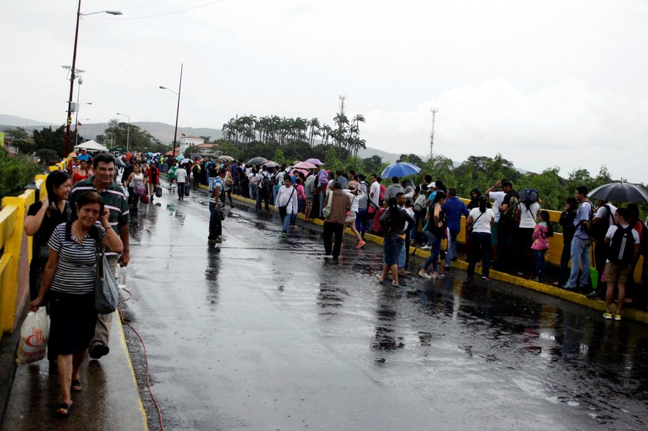 People line up, right, to cross over the Simon Bolivar international bridge to Colombia to take advantage of the temporary border opening as others come back after shopping in San Antonio del Tachira, Venezuela, July 16, 2016.