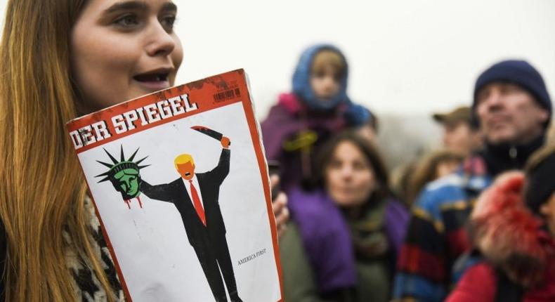 A young woman holds the last edition of Der Spiegel magazine with a cover designed by Edel Rodriguez, as she protests against the travel ban imposed by US President Donald Trump, on February 4, 2017, in Berlin