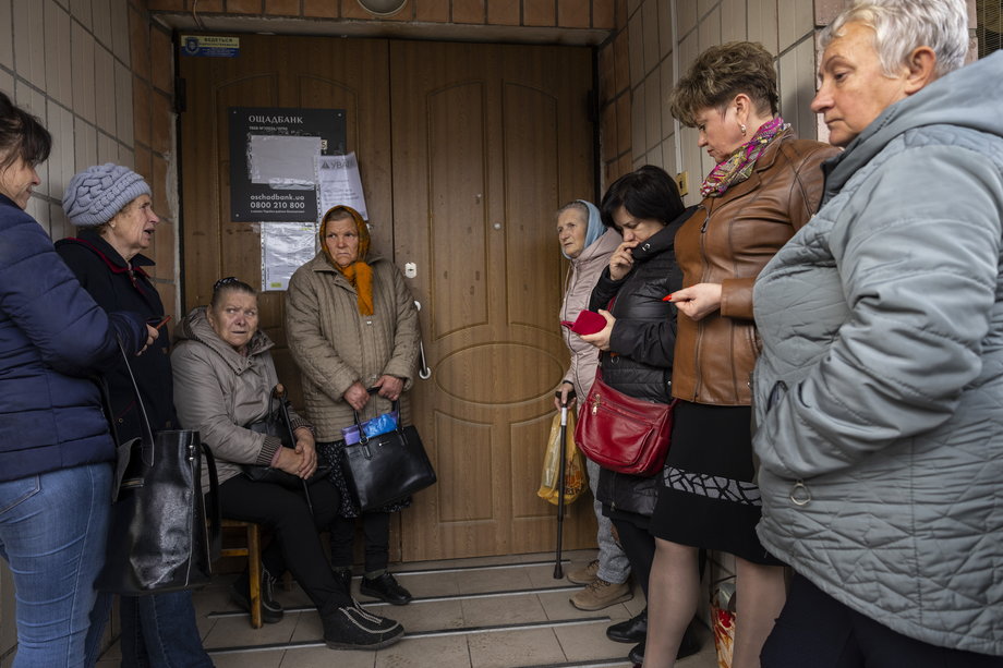 Klienci czekają przed bankiem podczas przerwy w dostawie prądu, 26 października 2022 r. w Borodziance na Ukrainie. 