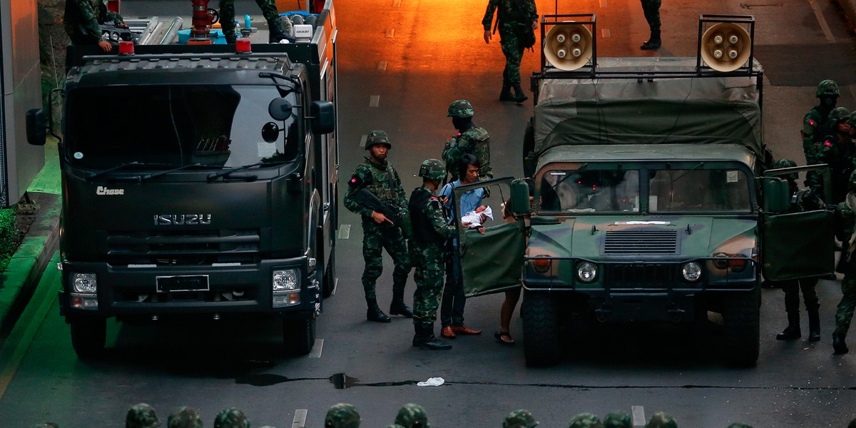 A couple with a baby enter a military vehicle as soldiers, deployed to control protesters against military rule, help them out of a protest area in Bangkok May 26, 2014.