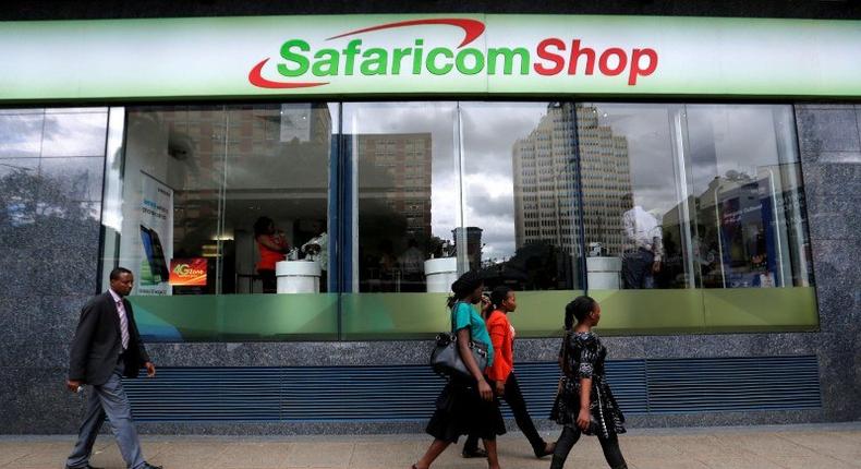 Pedestrians walk past a mobile phone care centre operated by Kenyan's telecom operator Safaricom in the central business district of Kenya's capital Nairobi, May 11, 2016. 