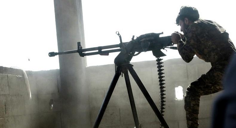 A fighter of the US-backed Syrian Democratic Forces fires a machine gun during their advance into the Islamic State group stronghold of Raqa on June 21, 2017