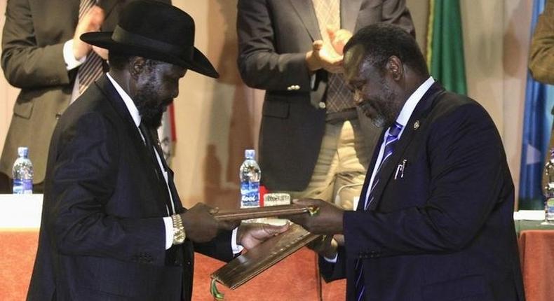 South Sudan's President Salva Kiir (L) and South Sudan's rebel commander Riek Machar exchange documents after signing a ceasefire agreement during the Inter Governmental Authority on Development (IGAD) Summit on the case of South Sudan in Ethiopia's capital Addis Ababa, Feburary 1, 2015. REUTERS/Tiksa Negeri