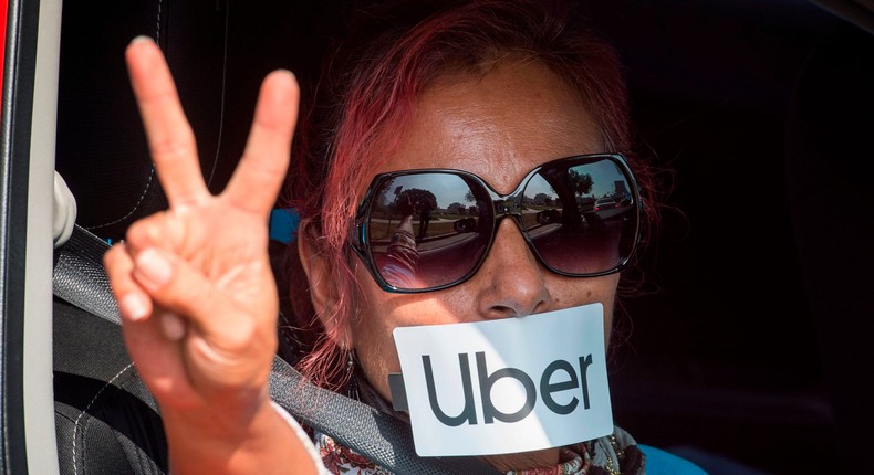 A protester gestures as Uber and Lyft drivers drive through Beverly Hills on their way to demonstrate outside the recently purchased $72 million home of Uber co-founder Garrett Camp, to protest the first day of an