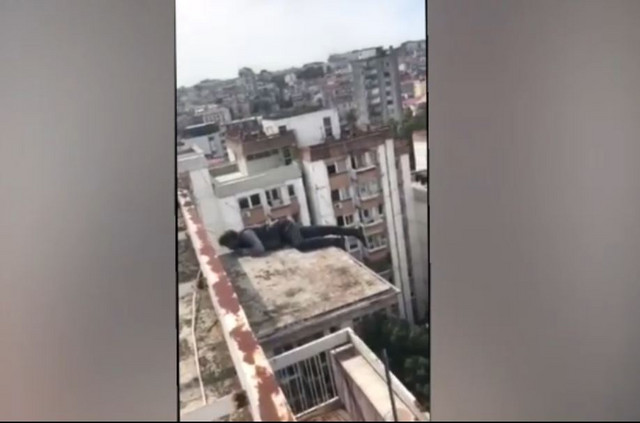 A man is lying on the roof canopy of the building.