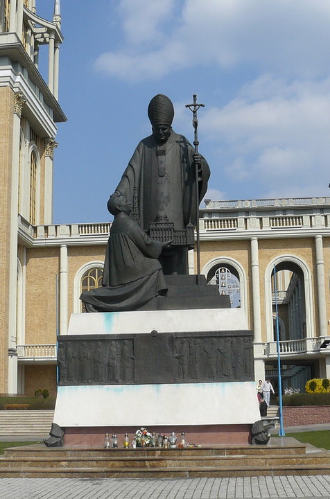 Rzeźba przed bazyliką. Pierwotnie na cokole znajdował się też ksiądz Eugeniusz Makulski, twórca licheńskiego sanktuarium. Jego postać została usunięta po wybuchu afery pedofilskiej z udziałem duchownego. 