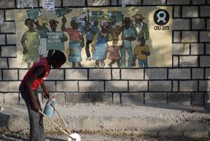 A boy playing with a homemade toy walks past an Oxfam sign in Corail, a camp for displaced people of
