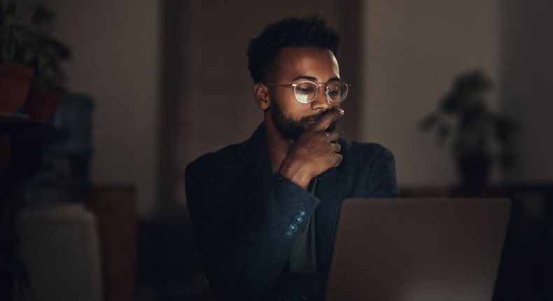 Shot of a young businessman using a laptop during a late night at work