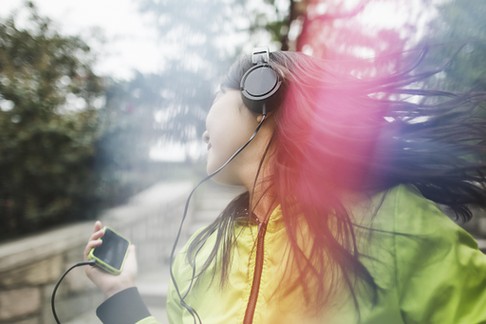 Young woman, outdoors, listening to music and dancing