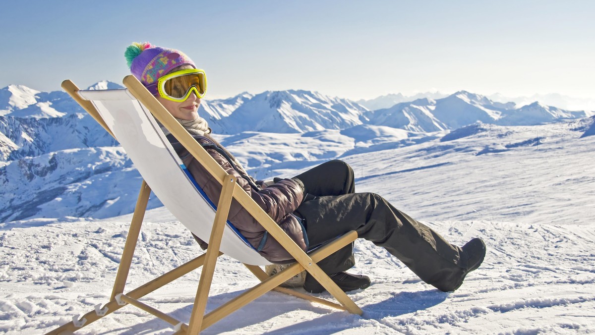 Girl sunbathing in a deckchair, snowy mountain landscape