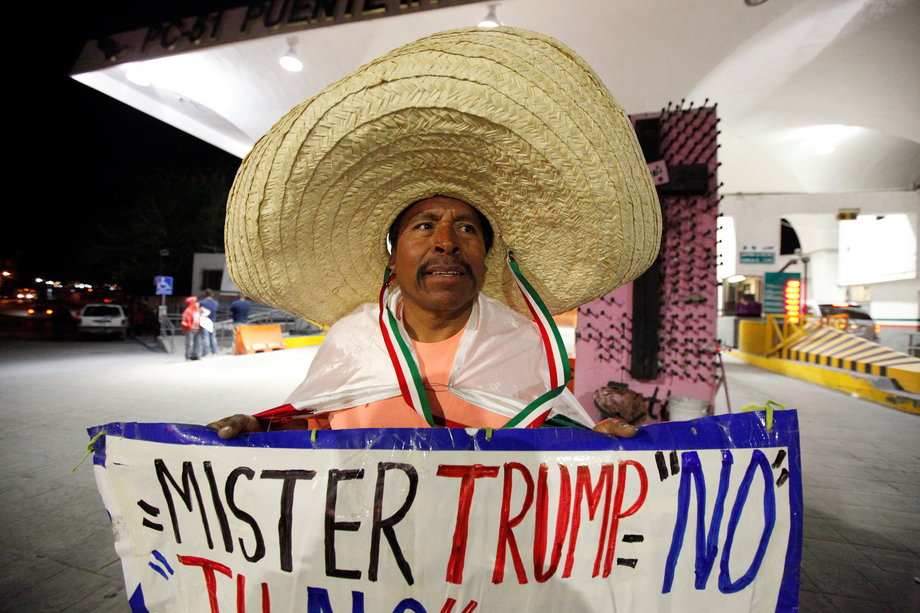 Martin Macias holds a placard against US Republican presidential nominee Donald Trump while standing at Paso del Norte international border crossing bridge in Ciudad Juarez, Mexico, November 8, 2016.