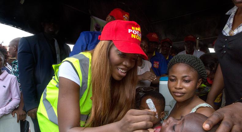 Tiwa Savage giving a child a polio vaccination 